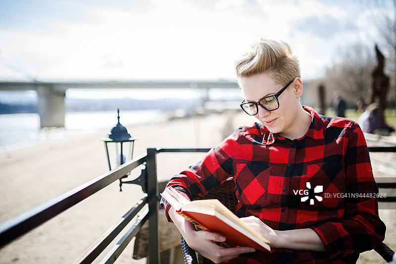 在河岸咖啡馆里看书的年轻漂亮女人图片素材