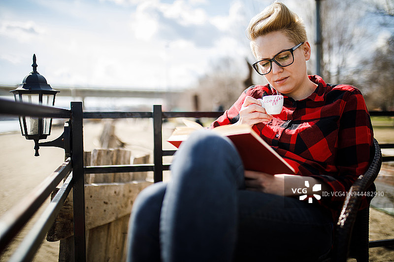 在河岸咖啡馆里看书的年轻漂亮女人图片素材