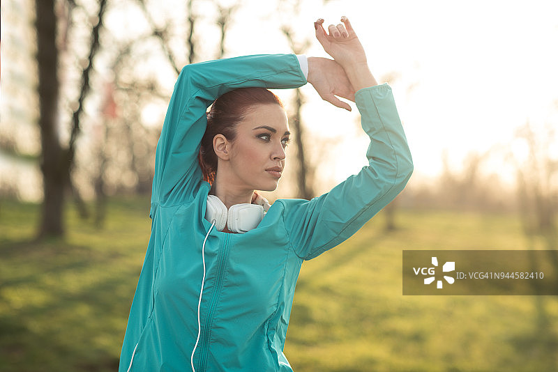 在户外训练中伸展手臂的健壮女人图片素材