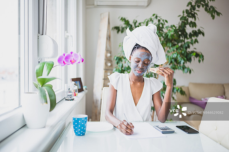 年轻的非洲裔美国女人在家工作，在厨房使用笔记本电脑图片素材