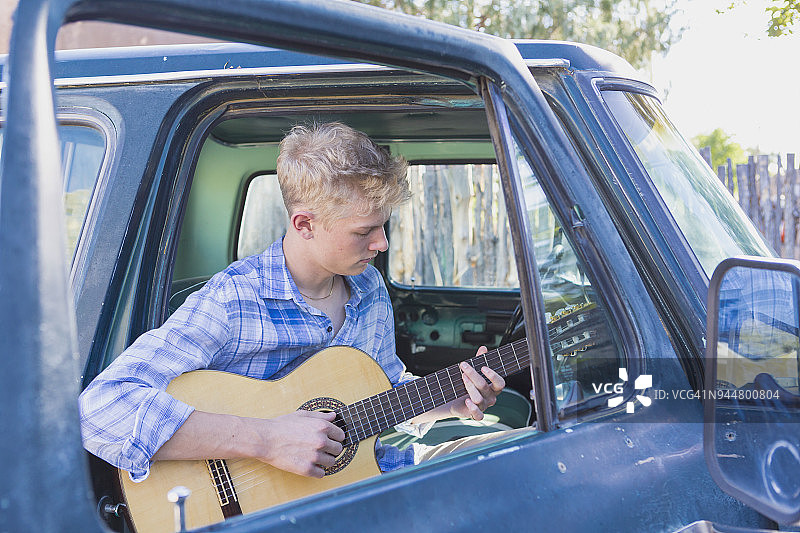 在皮卡车里弹吉他的青少年男孩图片素材