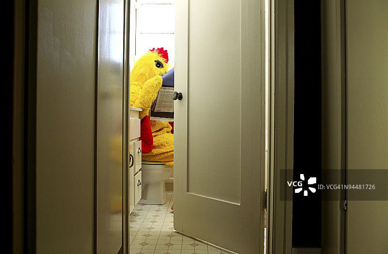 穿着小鸡服装坐在马桶上看报纸的人图片素材