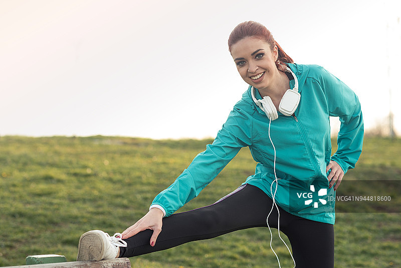 在公园长椅上伸腿的年轻女子图片素材