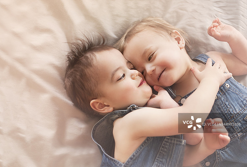 床上紧密裁剪的友爱双胞胎幼儿拥抱图片素材