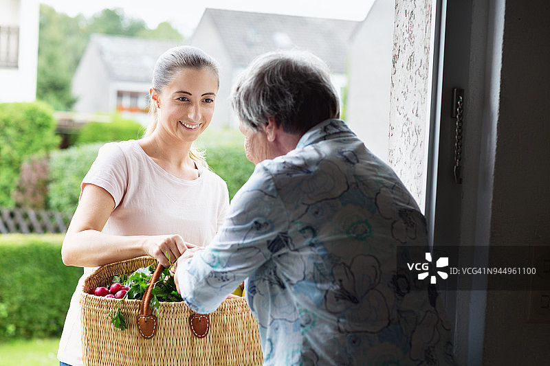 年轻护理员给年长妇女送食品杂货图片素材