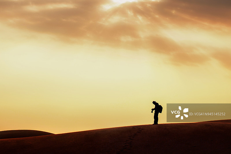 阳光明媚的沙漠中孤独的男人和脚印图片素材