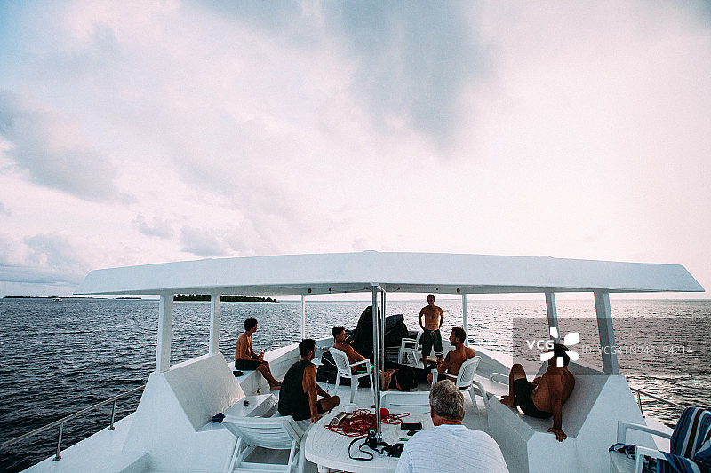 冲浪者朋友们在一天结束时在船上放松图片素材