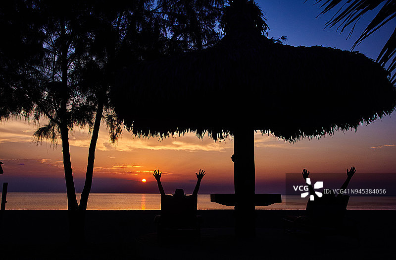 游客在海滩欣赏日落美景的剪影图片素材