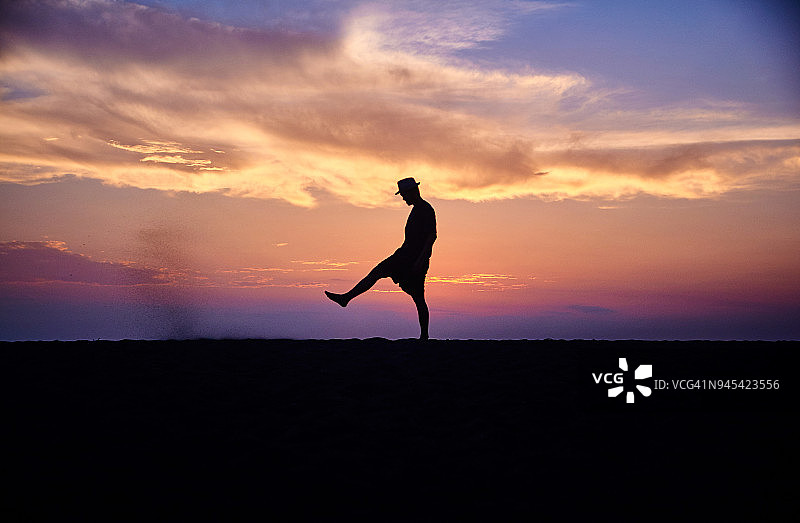 日落时分，在海滩跳舞的男人剪影图片素材
