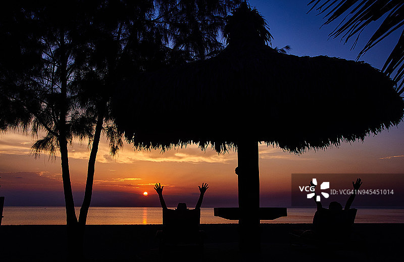 游客在海滩欣赏日落美景的剪影图片素材