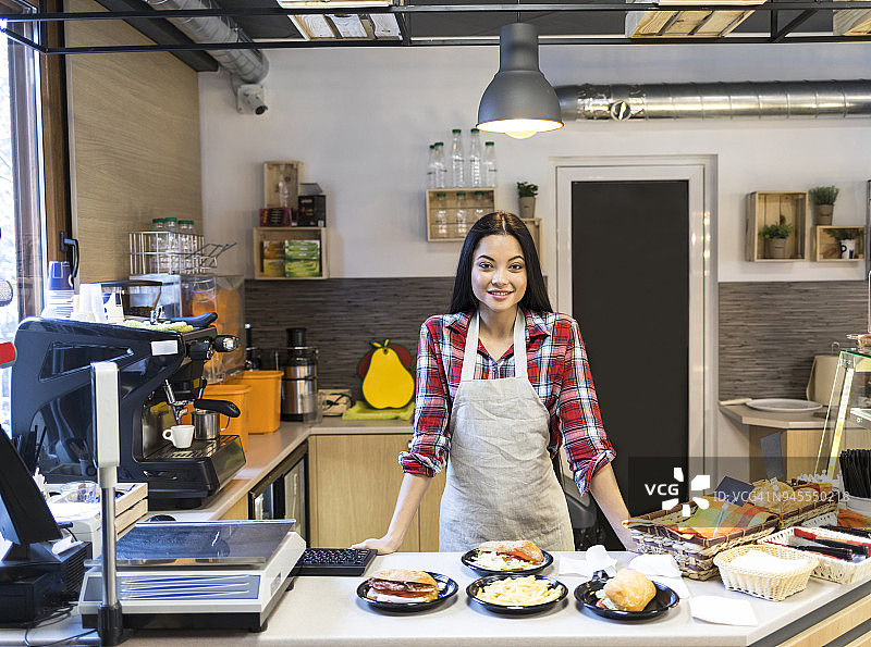 微笑的女服务员站在食品摊位后图片素材