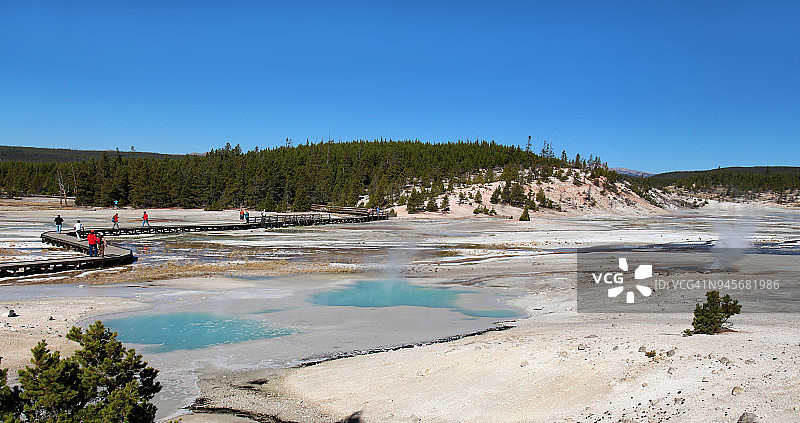 游客在怀俄明州黄石国家公园的诺里斯间歇泉盆地欣赏冒着蒸汽的地热池图片素材
