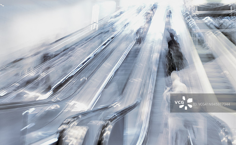 现代金属内饰中自动扶梯上的人群模糊背景图片素材