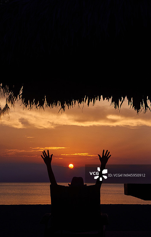 游客在海滩欣赏日落美景的剪影图片素材
