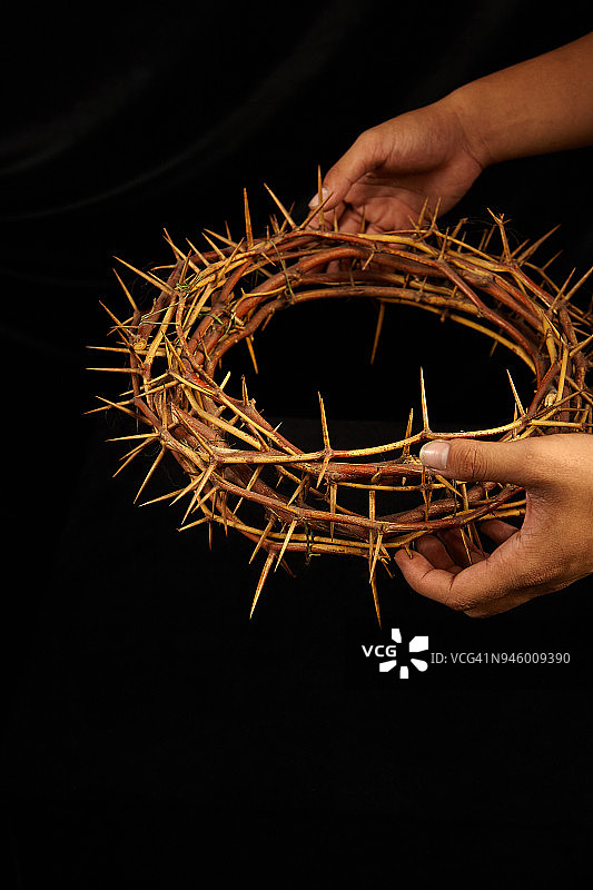 手持荆棘王冠，深色背景图片素材