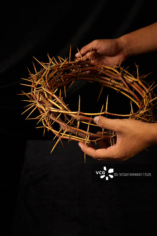 手持荆棘王冠，深色背景图片素材