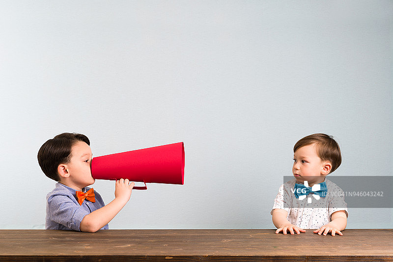 孩子用扩音器向另一个孩子喊话图片素材