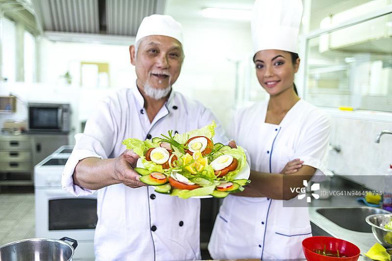 年长的厨师展示蔬菜沙拉图片素材