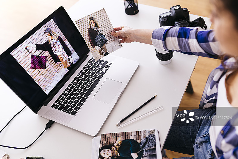在工作室看照片的时装设计师与笔记本电脑图片素材