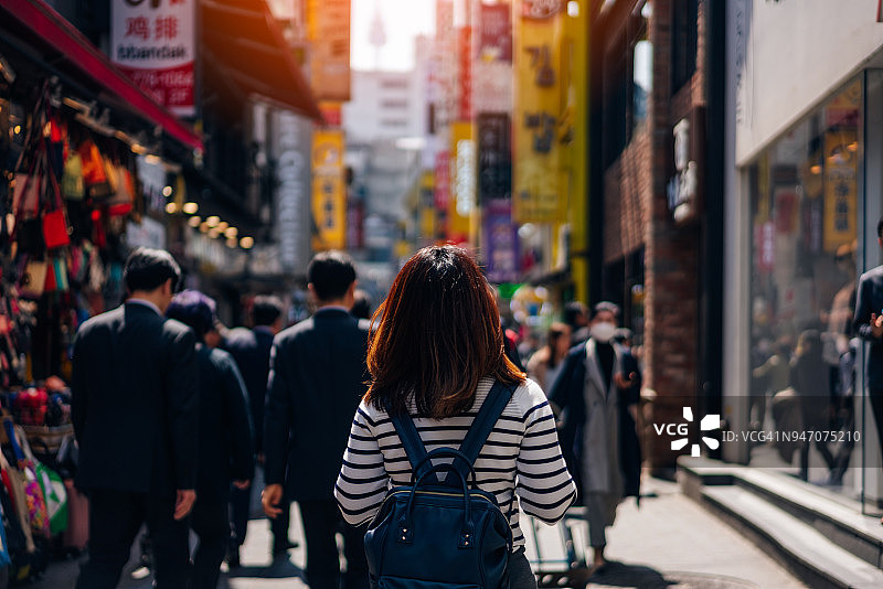 年轻亚洲女性游客在韩国首尔明洞街头市场旅游购物。明洞是首尔最受欢迎的购物市场。图片素材