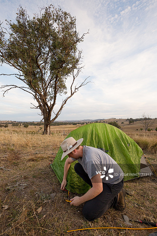 露营者将帐篷钉锤入坚硬的地面图片素材