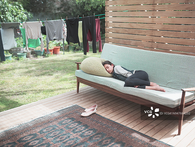 在花园里沙发上睡着的疲惫少女图片素材