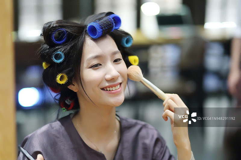 在沙龙里用卷发棒的年轻女子图片素材
