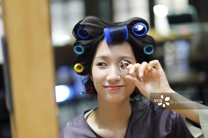 年轻女人在沙龙里使用睫毛夹图片素材