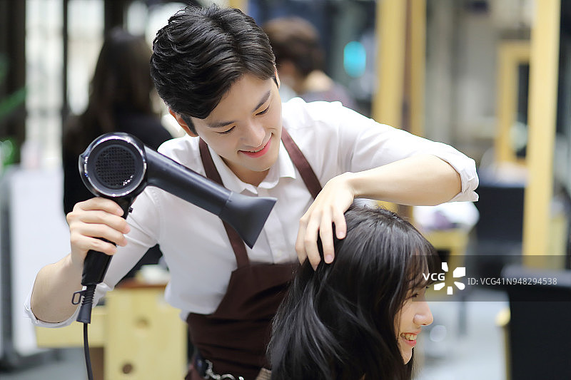 理发师用吹风机吹干顾客的头发图片素材