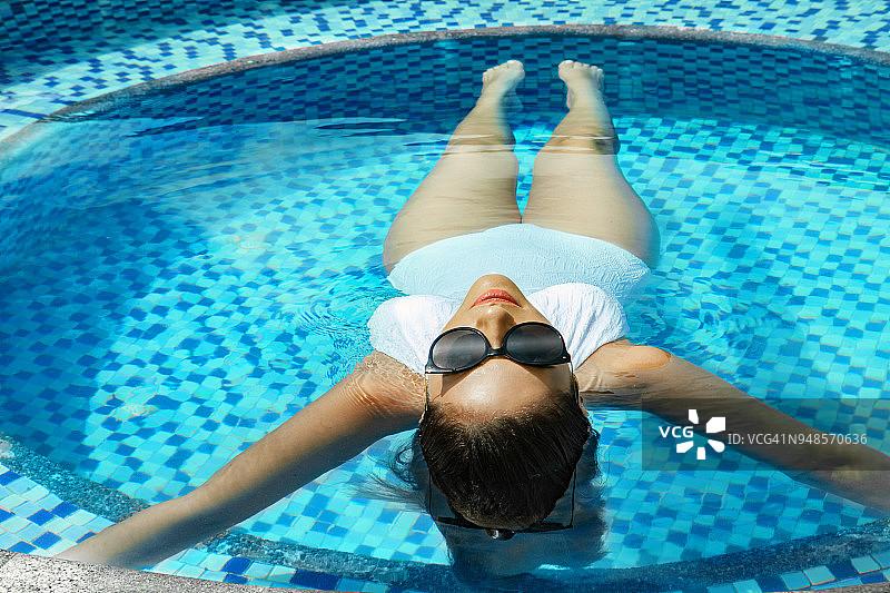 身穿白色泳衣在豪华酒店享受夏日假期的美丽女人图片素材