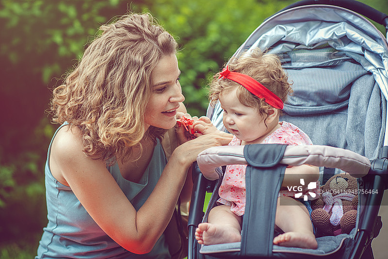 母亲和她的女儿在公园的婴儿车里图片素材