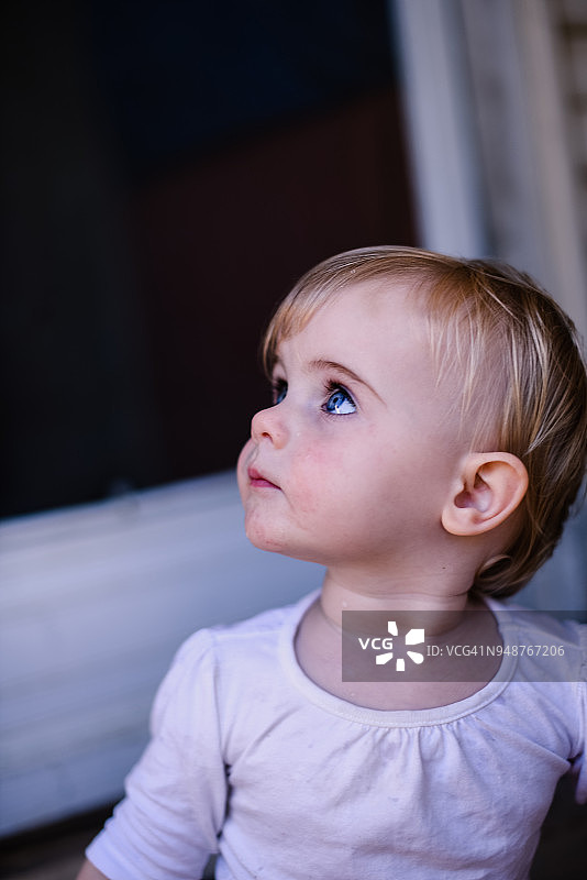 一岁女孩坐在地上，看向侧面图片素材