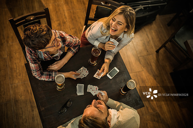 俯视：快乐的朋友在酒吧玩牌图片素材