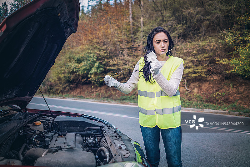 女人在检查她的汽车的油位图片素材