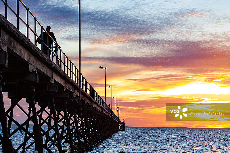 日落时分沿码头行走的人的剪影-澳大利亚南部的塞杜纳图片素材