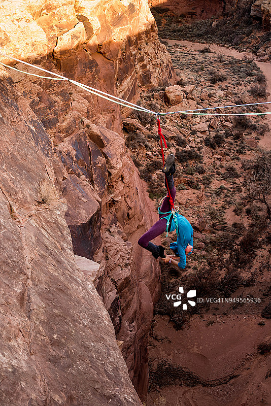 在犹他州莫阿布附近走扁带或走绳的女性极限运动员图片素材