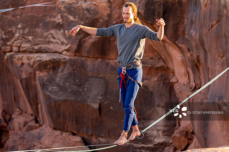 在犹他州拱门国家公园高空扁带上运动的年轻男子图片素材