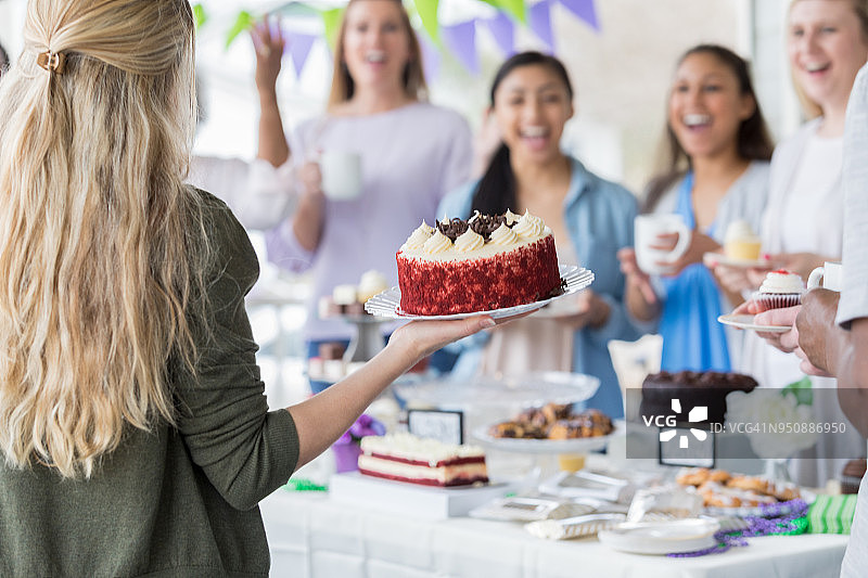 女人送捐赠蛋糕去义卖图片素材