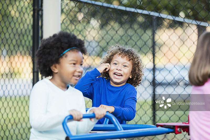 混血男孩和朋友在游乐场旋转木马上玩耍图片素材