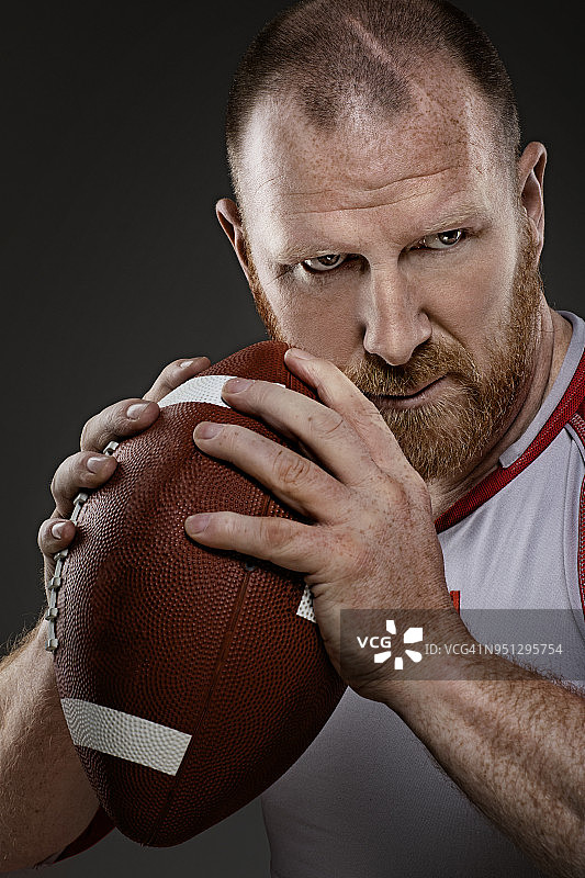 留着胡子的红发成年男子橄榄球运动员手持橄榄球图片素材