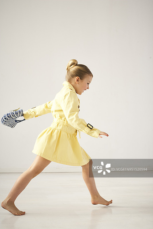 在浅色背景前赤脚奔跑的快乐小女孩图片素材
