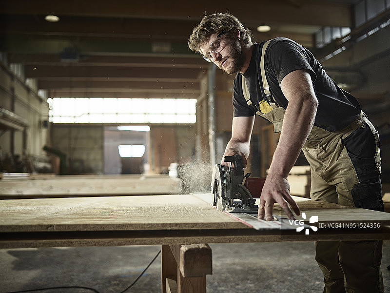 木匠用手锯锯木头图片素材