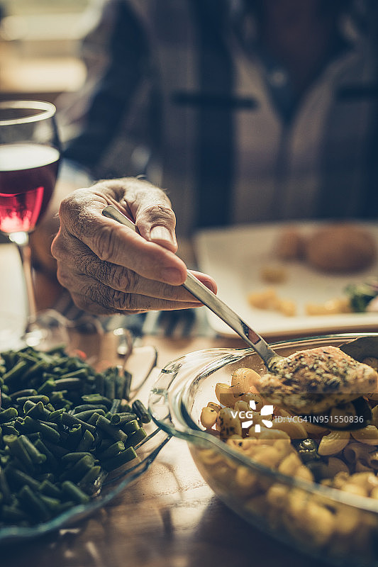 特写：身份不明的老年男人在餐桌上用餐图片素材