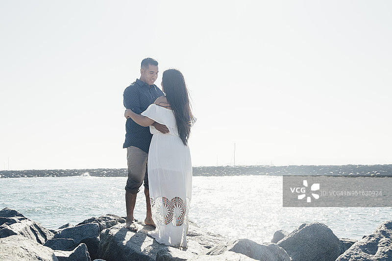 一对夫妇在海滩岩石上面对面站立，美国加利福尼亚州海豹滩图片素材