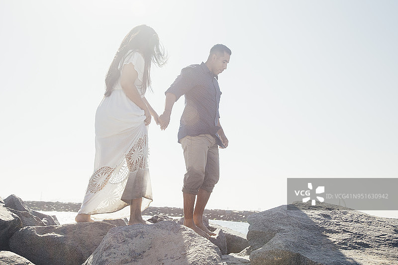 情侣站在沿海岩石上，低角度视角，美国加利福尼亚州海豹滩图片素材