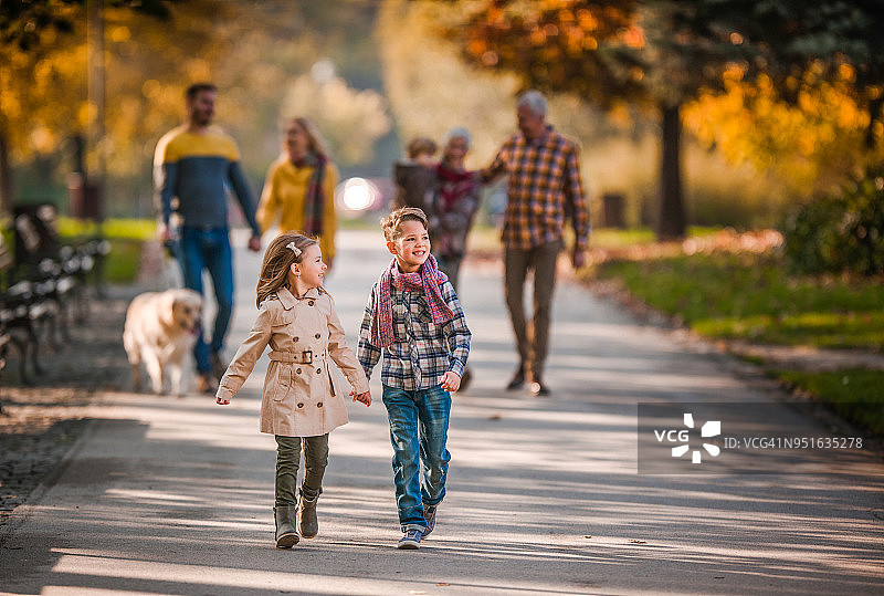 手牵着手走在户外家人面前的快乐兄弟姐妹图片素材