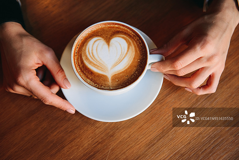 女人手拿卡布奇诺图片素材