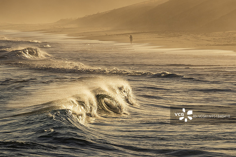 海景：海滩日落时的海浪与人图片素材