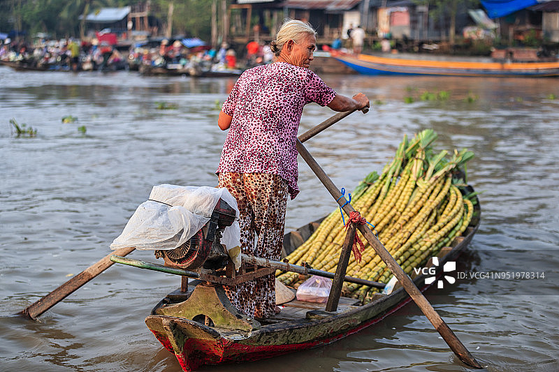 越南妇女在湄公河三角洲水上市场出售甘蔗图片素材
