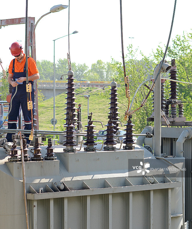 在发电站高压变压器上工作的电工图片素材
